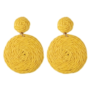 Detailed macro view of yellow raffia woven round drop earrings with golden metal rings