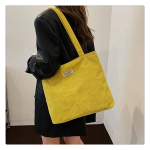 Detail of bright yellow corduroy tote bag showing textured fabric and white woven label