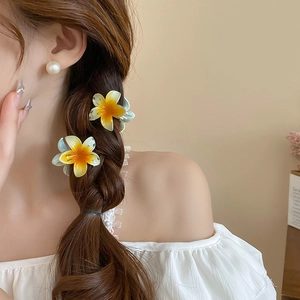 Close-up of blue and orange plumeria flower hair clips styled on a braided hairstyle