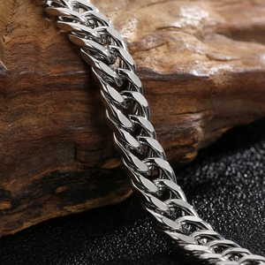 Polished silver cuban link chain bracelet for men with OT buckle on a rustic wood background