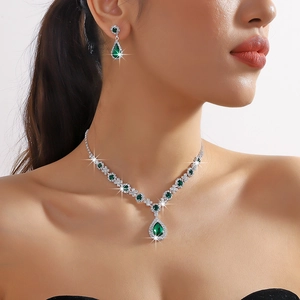 Detail of emerald teardrop necklace and earrings set worn by a model for elegant look