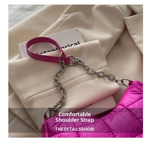 Macro detail of magenta quilted crescent bag with silver chain on ivory blazer