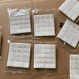 Close-up of 12 white round double-sided adhesive dots in a clear plastic bag