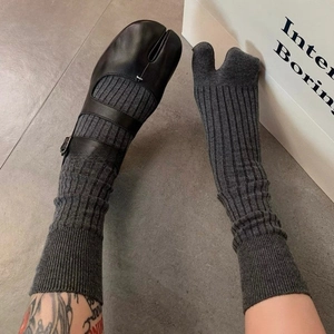 Detail of dark grey split toe socks worn with black Mary Jane tabi shoes on grey floor