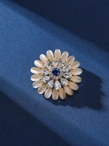 Macro shot of sun flower brooch featuring opal petals and blue zircon center on metal