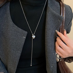 Close-up of a silver Y-shaped necklace with heart pendant on a professional model