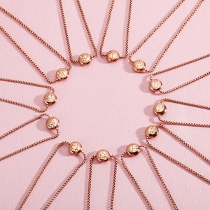 Rose gold zodiac bracelets set with rhinestones on a pink textured background
