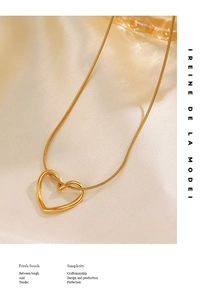 Detailed close-up of 18K gold plated hollow heart pendant on soft beige silk fabric