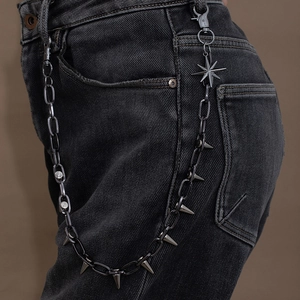 Detail of punk jeans chain with metal spikes and octagonal star pendants on denim