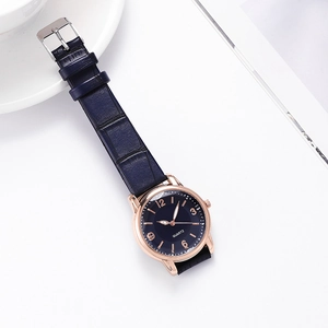 Close-up of blue quartz watch dial with gold numerals and matching leather strap