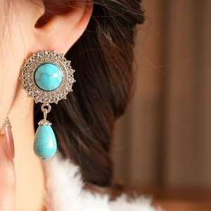 Close-up of vintage silver earrings with turquoise stones and shimmering crystal halo
