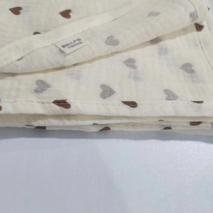 Detailed macro shot of organic cotton muslin cloth with brown heart patterns and safety tag