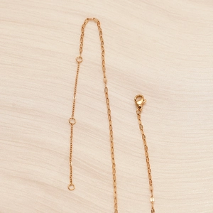 Macro detail of rose gold stainless steel necklace chain with lobster clasp and link rings