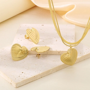 Detailed set of 18K gold plated heart jewelry with ripple texture on stone background