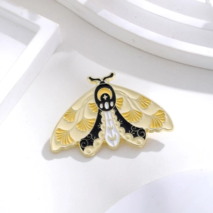 Macro detail of moth enamel brooch with star and moon patterns and golden outlines