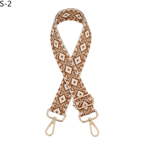 Detail of adjustable rhombus pattern fabric strap with gold metal buckle and swivel hooks