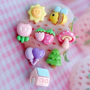 Flat lay of 8 colorful resin charms including bees, mushrooms, and trees for DIY crafts