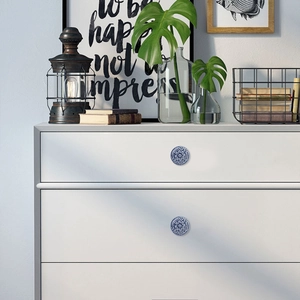Detailed view of blue floral ceramic knobs installed on a white vintage drawer chest