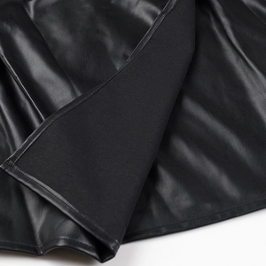 Vue détaillée de la texture du cuir PU noir et des coutures fines sur la robe