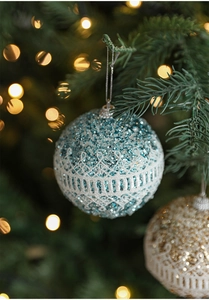 Detail of glittery Christmas foam balls with white lace trim hanging on a festive tree
