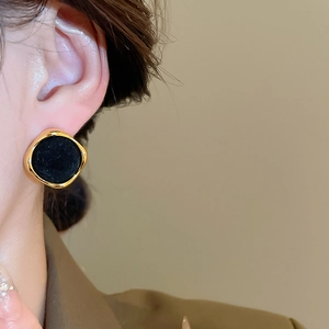 Close-up of a model wearing vintage geometric gold earrings with black velvet inlay