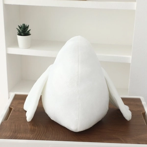 Back view of cute white plush pigeon bird toy on a wooden tray in a home setting