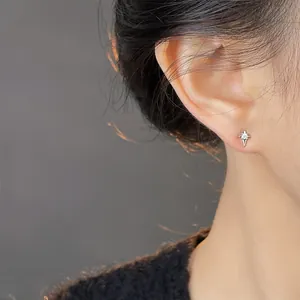 Macro shot of minimalist silver star stud earring with small diamond on female model