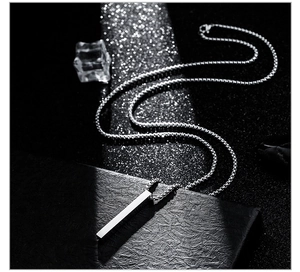 Close-up of minimalist silver stick pendant on titanium steel chain over textured surface