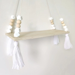 Detail of Nordic wooden wall shelf with white macrame tassels and octagonal beads