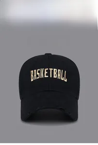 Close-up of gold embroidered basketball text on black baseball cap with distressed brim