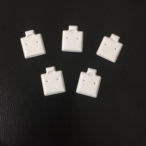 Vijf stuks witte vierkante PVC-oorknopjes displaykaarten op zwart getextureerd leer