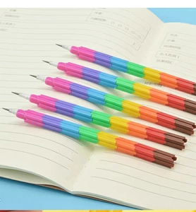 Detailed view of 5 stackable rainbow pencils placed on an open notebook with bright colors