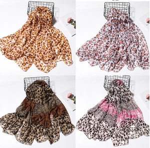 Detail view of four leopard print scarves in brown, pink, and grey draped on a wire basket