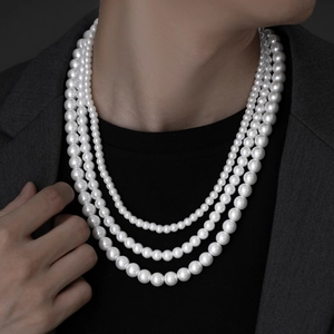 Close-up of a three-layer pearl necklace with graduated beads on a grey suit model