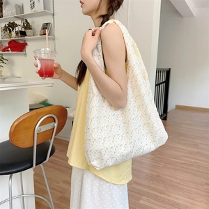 Detailed side view of floral lace tote bag with yellow embroidery on cream fabric