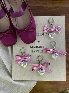 Detail of silver heart pendants with bright pink bows on a beige book surface