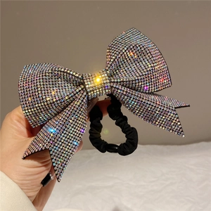 Detailed close-up of a large rhinestone bow hair tie with iridescent crystal embellishments