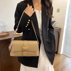 Detail of beige textured leather shoulder bag featuring gold D-ring and printed silk scarf