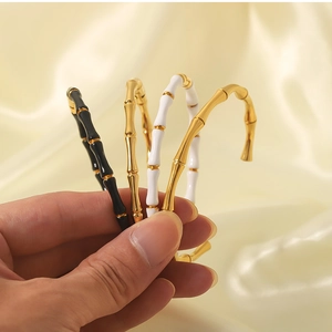 Detailed close-up of bamboo-style stainless steel cuffs in gold, black and white finishes