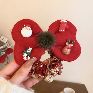 Close-up of a festive red bow hair tie with Christmas resin charms and checkered fabric