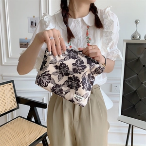 Detail of floral cotton makeup bag with black flower print and branded woven label