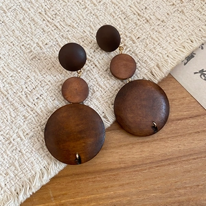 Détail macro de boucles d'oreilles en bois brun à disques gradués sur surface tissée
