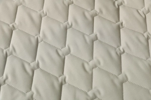 Detailed macro view of geometric quilted pattern on warm winter padded cotton jacket fabric