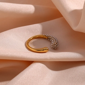 Detail of gold C-shaped open ring featuring micro-set small pearls on soft silk fabric