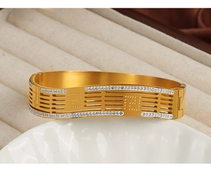 Detailed shot of gold-plated open bangle with geometric cut-outs and inlaid crystals