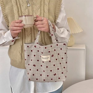Detailed embroidery of red polka dots and bows on checkered canvas commuter bag