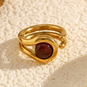 Detailed close-up of an 18K gold double-layered ring featuring a deep red gemstone bead