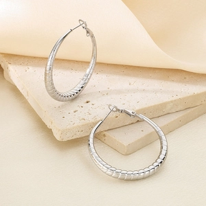 Macro detail of silver S925 engraved hallmark on large textured stripe hoop earrings