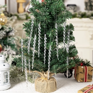 Clear acrylic icicle ornaments hanging on a Christmas tree with festive holiday decor