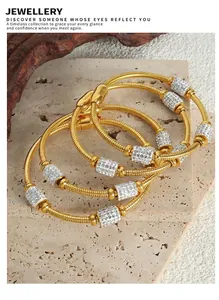 Detailed view of three 18K gold plated snake chain bracelets with zircons on stone tray